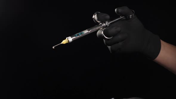 Dentist Hand in Black Glove Holding Syringe with Anesthesia Releasing Drug Drop By Drop. Usage of