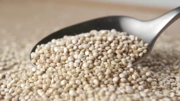 Spoon spreads raw uncooked quinoa in slow motion