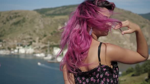 Portrait of a Smiling Girl with Pink Hair Mountains and Water in the Background
