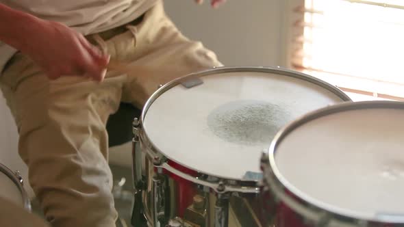 Drummer playing paradiddle rudiment with gorgeous light entering the room.