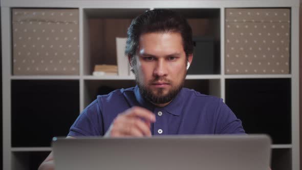 Busy man typing on laptop doing research. Young male professional using computer sitting at home.