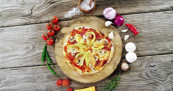 Italian pizza on wooden table with vegetables and spices