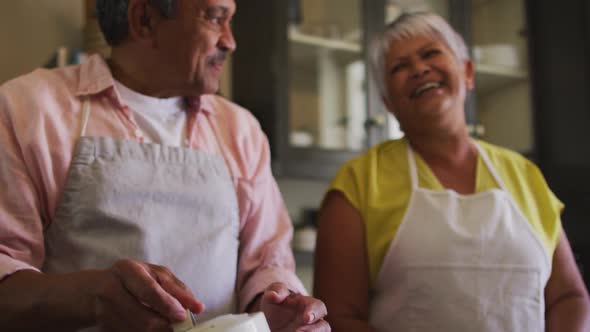 Happy senior mixed race couple preparing food together in kitchen