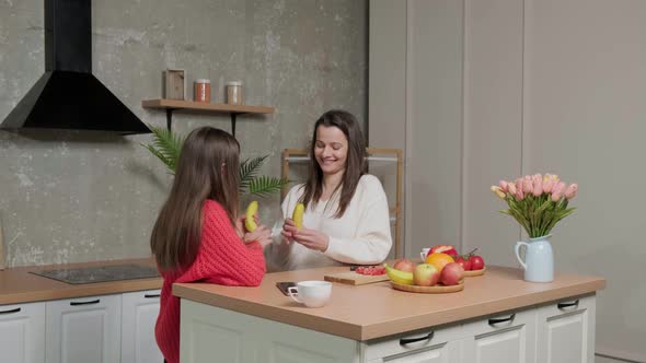 Happy Mother Talking to Her Daughter While They Eat a Banana