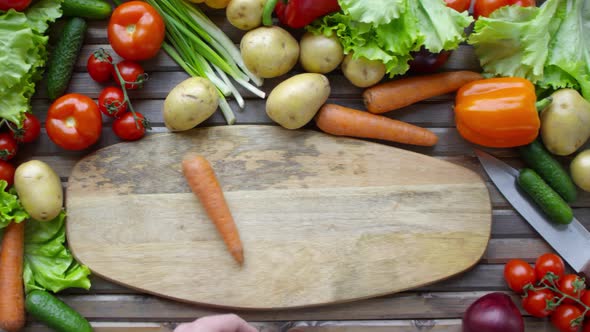 Male Hands Rolling Carrot on Cutting Board