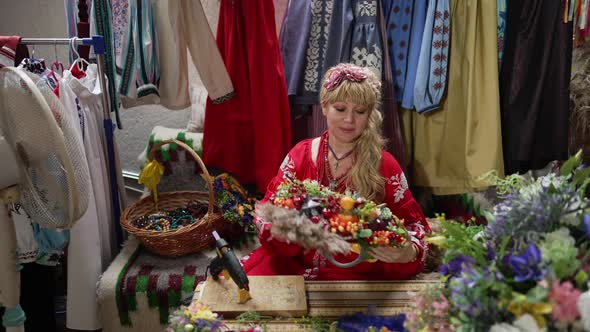 Portrait of Beautiful Ukrainian Woman in Traditional Embroidered Dress Making National Head Wreath