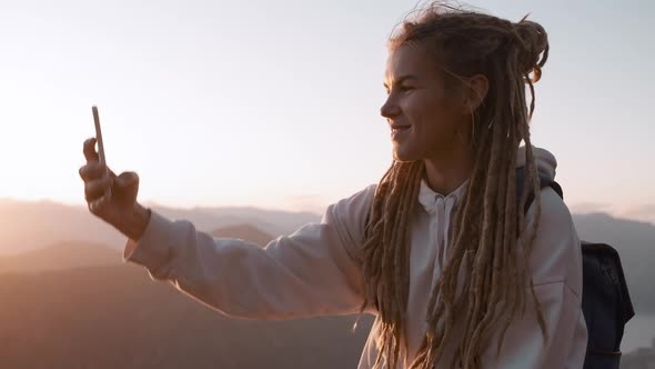Happy active Dreadlocks woman taking photo selfie with cell phone against Montenegro
