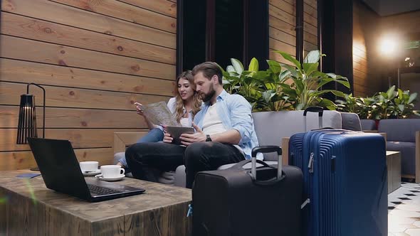 Couple which Sitting Together in Hotel Lobby and Using Tourist Map and Tablet PC