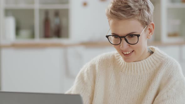 Smiling Woman Doing Online Shopping on Laptop and Drinking Tea at Home