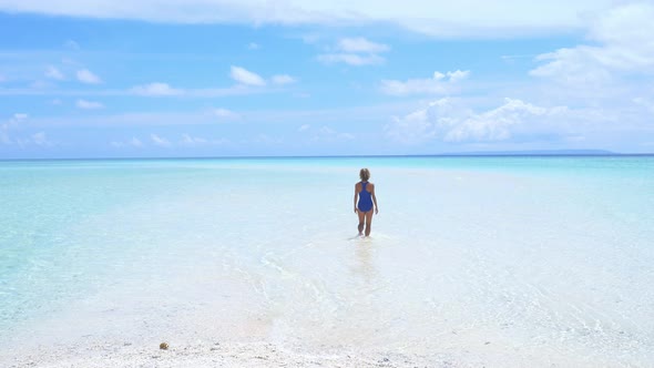 Woman sunbathing walking in turquoise water white sand beach tropical sea