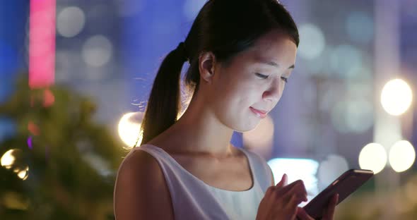 Woman use of mobile phone in city at night