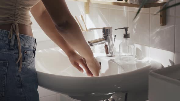 Unrecognisable Woman Washing Hands in White Sink