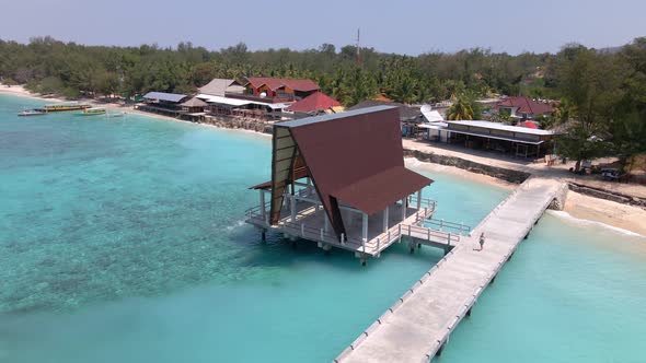 Woman running on wooden jetty during beautiful weather at pier of Gili Meno Island with luxury Hotel