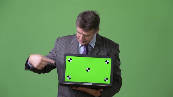 Mature Handsome Businessman Against Green Background