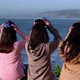 group of three women looking at the sea, putting on colorful caps from pichilemu, punta de lobos - VideoHive Item for Sale