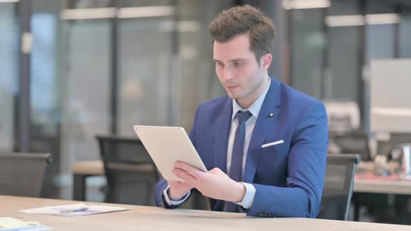 Businessman Celebrating Success on Tablet in Office