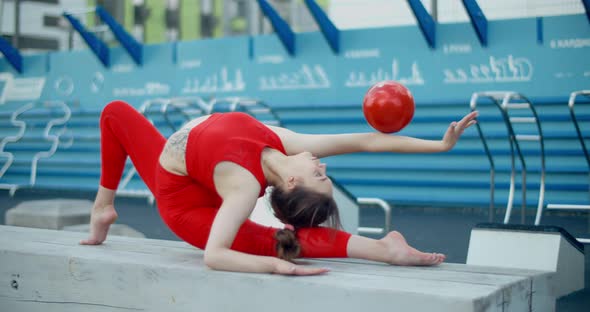 Woman in Red Sports Costume Performing Callisthenics Exercises with Gymnastic Ball at Workout