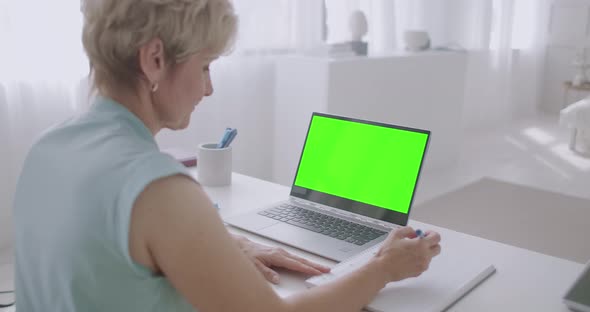 Aged Woman Is Learning Online, Viewing Training Webinar on Green Screen of Laptop for Chroma Key