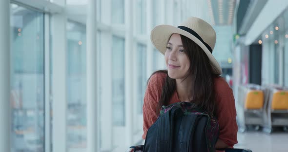 Woman go travel and look out of the window in the airport