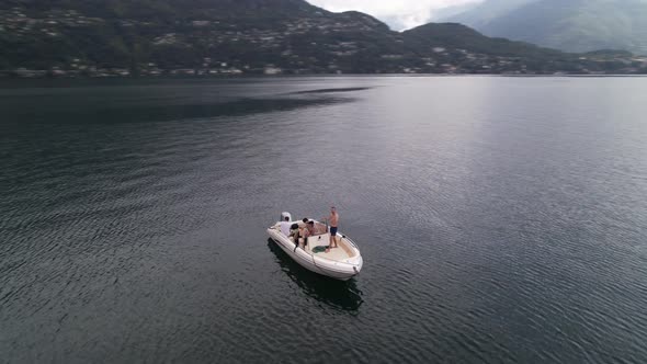 Young group of friends on a small boat in the middle of a lake, fast orbit, drone.