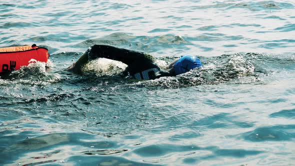 Male Open Water Swimmer Swimming with a Brightly Coloured Buoy Attached To Him