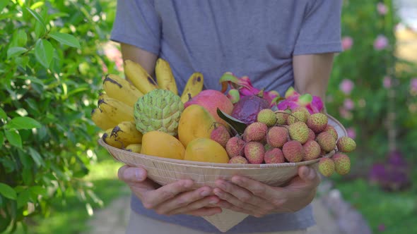 Variety of Fruits in a Vietnamese Hat. A Man in a Vietnamese Hat Holds a Hat Full of Tropical Fruits