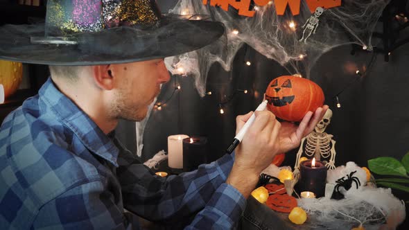 Man painting  pumpkin face, preparing festive Halloween decor