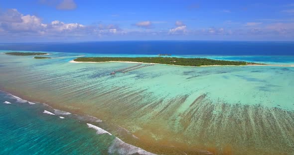 Aerial drone view of scenic tropical island and resort hotel with overwater bungalows in Maldives.