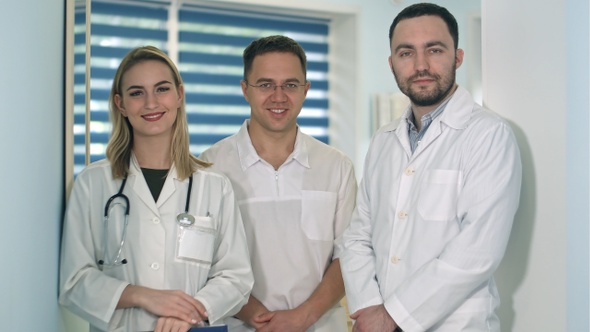 Two male doctors and female doctor with stethoscope smiling