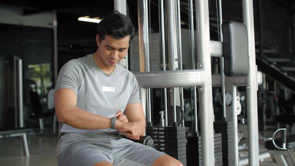 Asian Sportsman Using Smartwatch in Gym