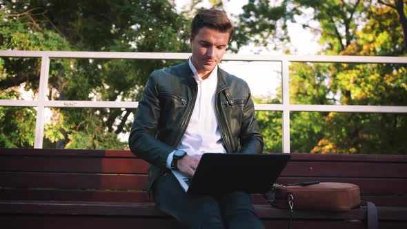 Young Handsome Man Using Laptop Sitting on Bench in Park