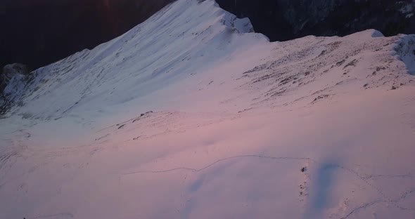 Aerial drone view of snow covered Alps mountains in the winter at sunset.