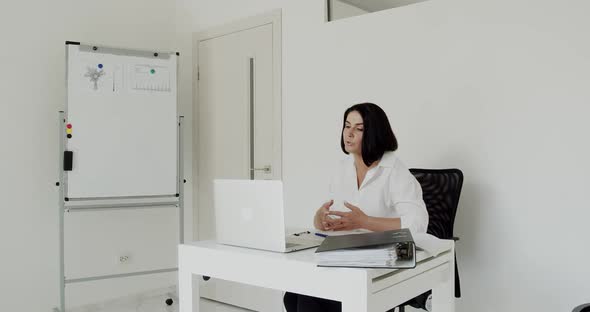 The Teacher Conducts an Online Lecture on a Laptop in the Office