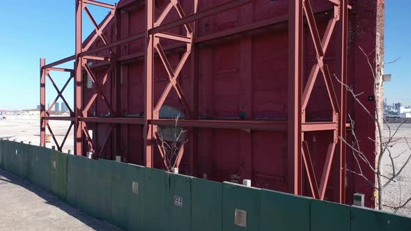 A low angle shot of an old building's red facade behind a green wooden fence. The camera boom up to