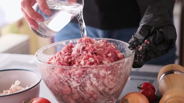 Adding Water to Minced Meat with Onion and Spices in a Glass Bowl Making Cutlets