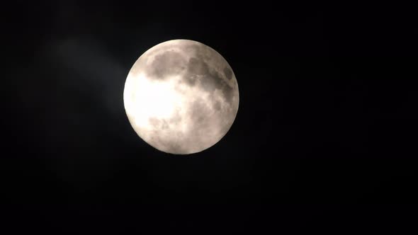 Clouds passing by the full moon, real time shot. Full moon at night with clouds in real time.