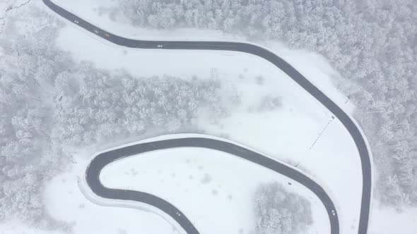 Aerial Drone Top View Serpentine Asphalt Road with Traffic Automobile Transport Snowy Mountain