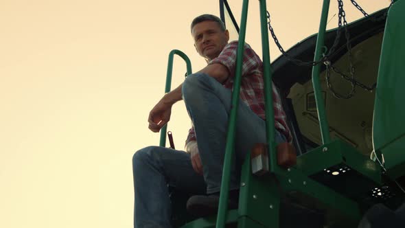 Successful Farmer Resting Tractor at Sunset