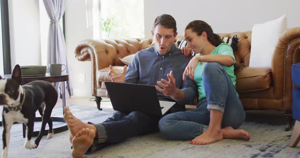 A young caucasian couple talking and paying their bills using a laptop