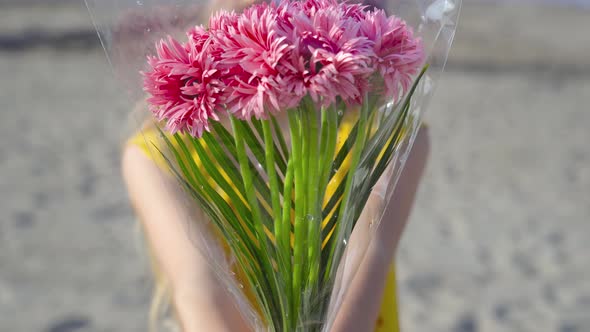 Teenager Holds a Bouquet of Flowers in Hand and Looks Forward with Serious Look