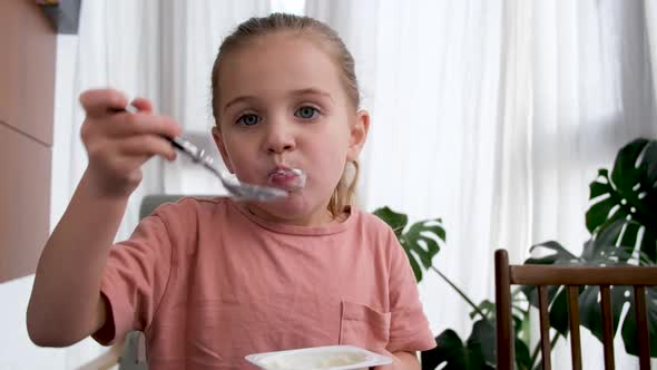 Little Girl Eats Delicious Yogurt for Breakfast at Home