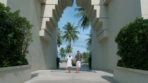 Couple Men and Woman Walking at an Old Gate During Vacation at an Luxury Resort