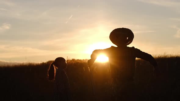 A Teenager Looks with Curiosity at a Scarecrow with a Pumpkin Head in the Field It Comes to Life and