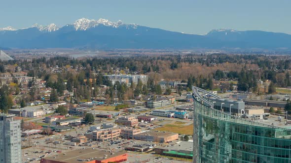 A Snow-Capped Mountain is Juxtaposed with a Modern Glass Condo Tower in Surrey, British Columbia Can