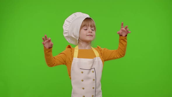 Child Girl Kid Dressed in Apron and Hat Like Chef Cook Baker Raising Hands Showing Tasty Gesture