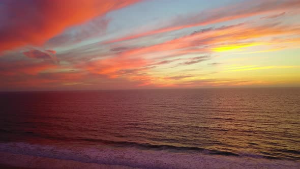 Aerial drone view of a sunset at the beach over the ocean.