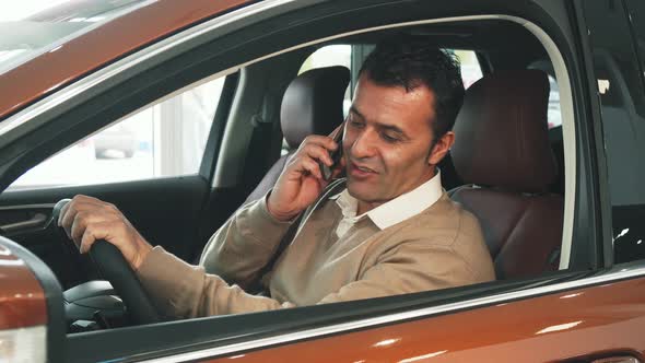 The Pleased Man Sitting in the Car and Talking on the Phone