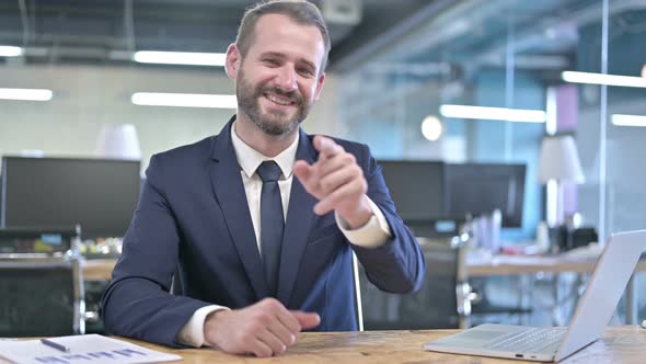 Cheerful Young Businessman Pointing Finger and Inviting