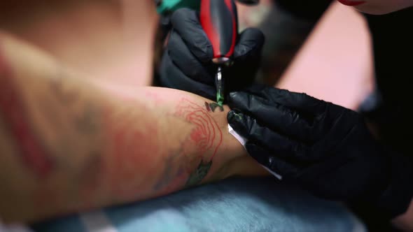 A Closeup View of a Professional Woman Tattooist Who is Tattooing on the Leg of a Young Girl