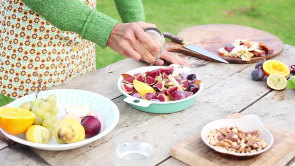 Woman adding seasonings to cut-up fruits